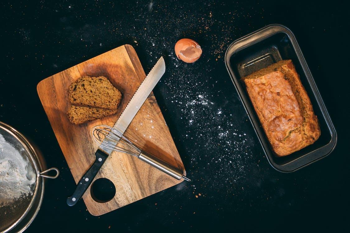 loaf of banana bread in a baking dish next to a cutting board