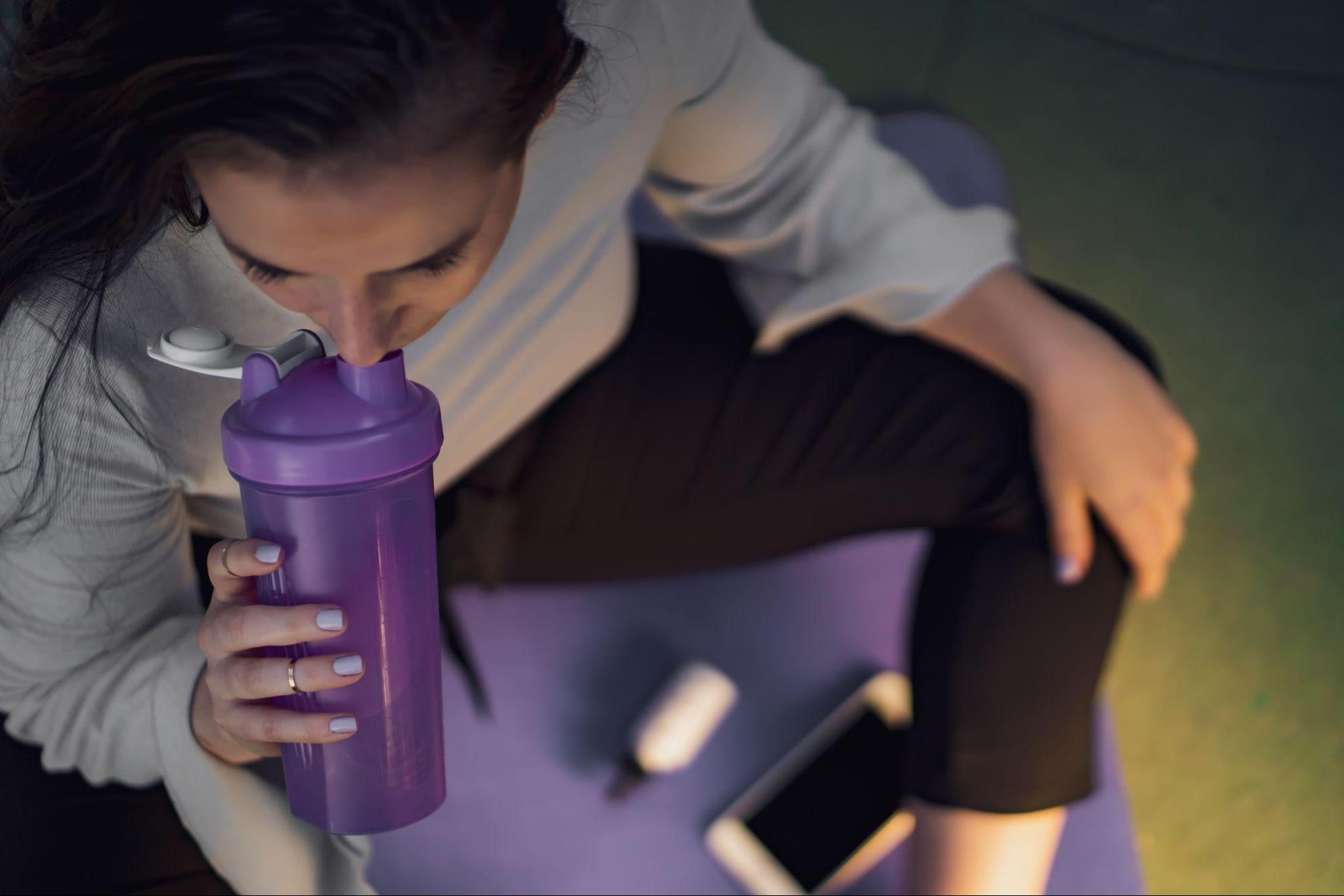  fit woman drinking BCAAs supplement from shaker bottle