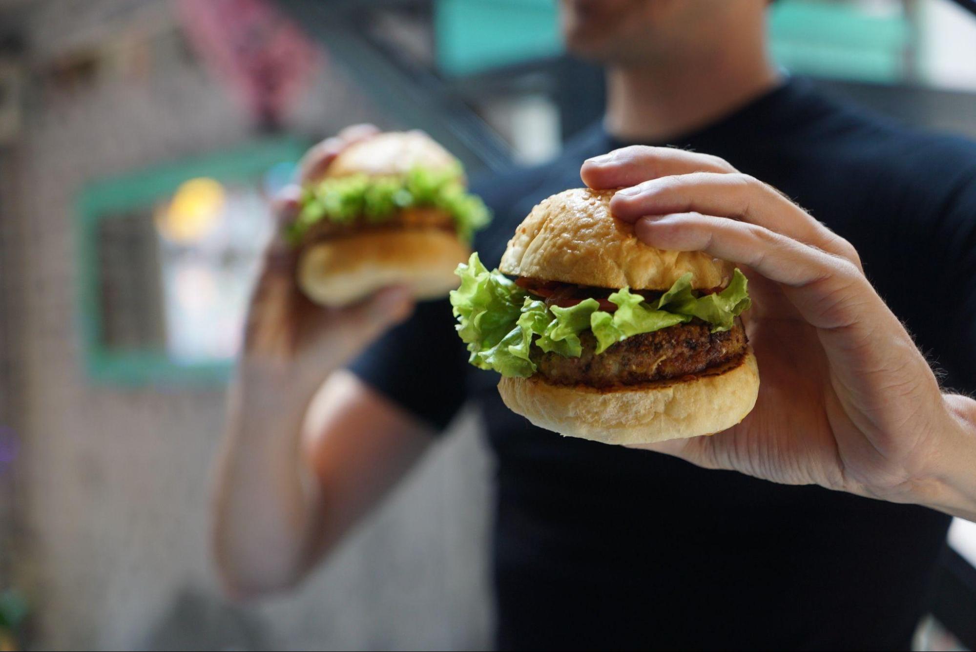  a man holding out two burgers