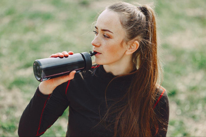 an athletic woman drinking water