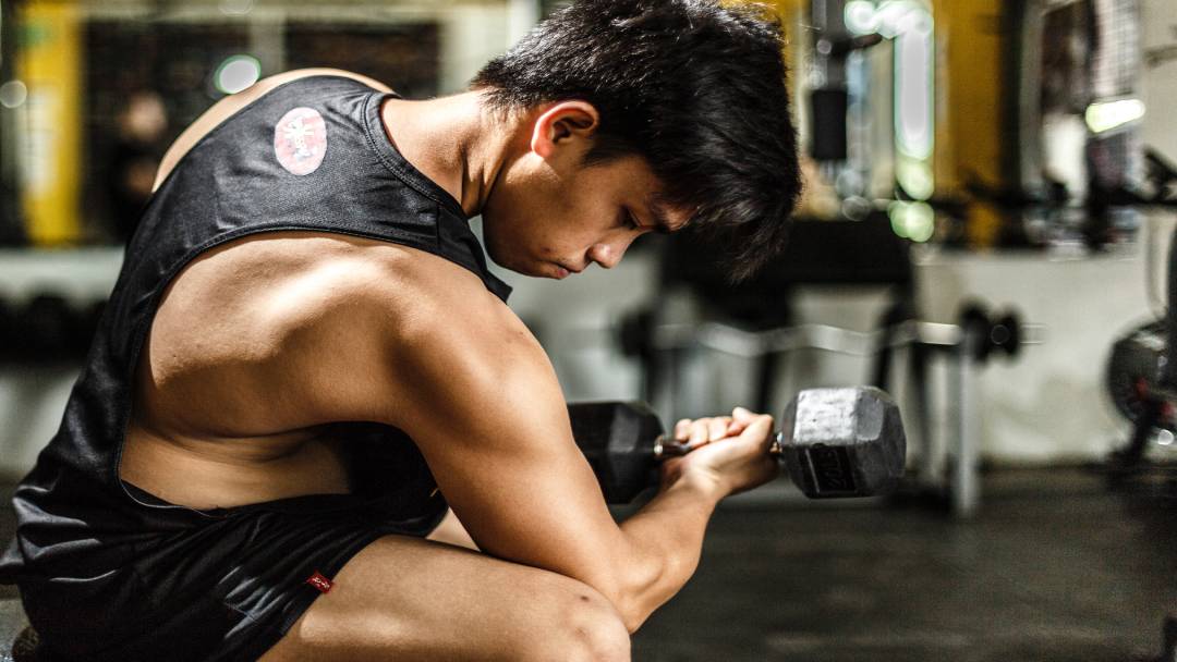 person flexing arm muscles with barbell